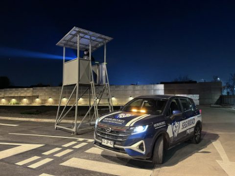 Guardia de ASCOR Security en una torre de vigilancia nocturna, con el vehículo institucional estacionado al frente