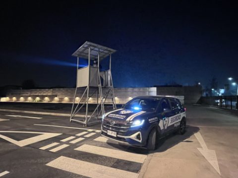 Vehículo de ASCOR Security con la baliza encendida junto a una torre de vigilancia, de noche