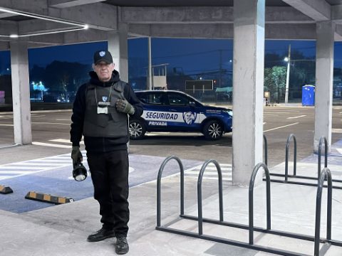 Guardia de ASCOR Security en su puesto, con linterna en la mano y credencial visible